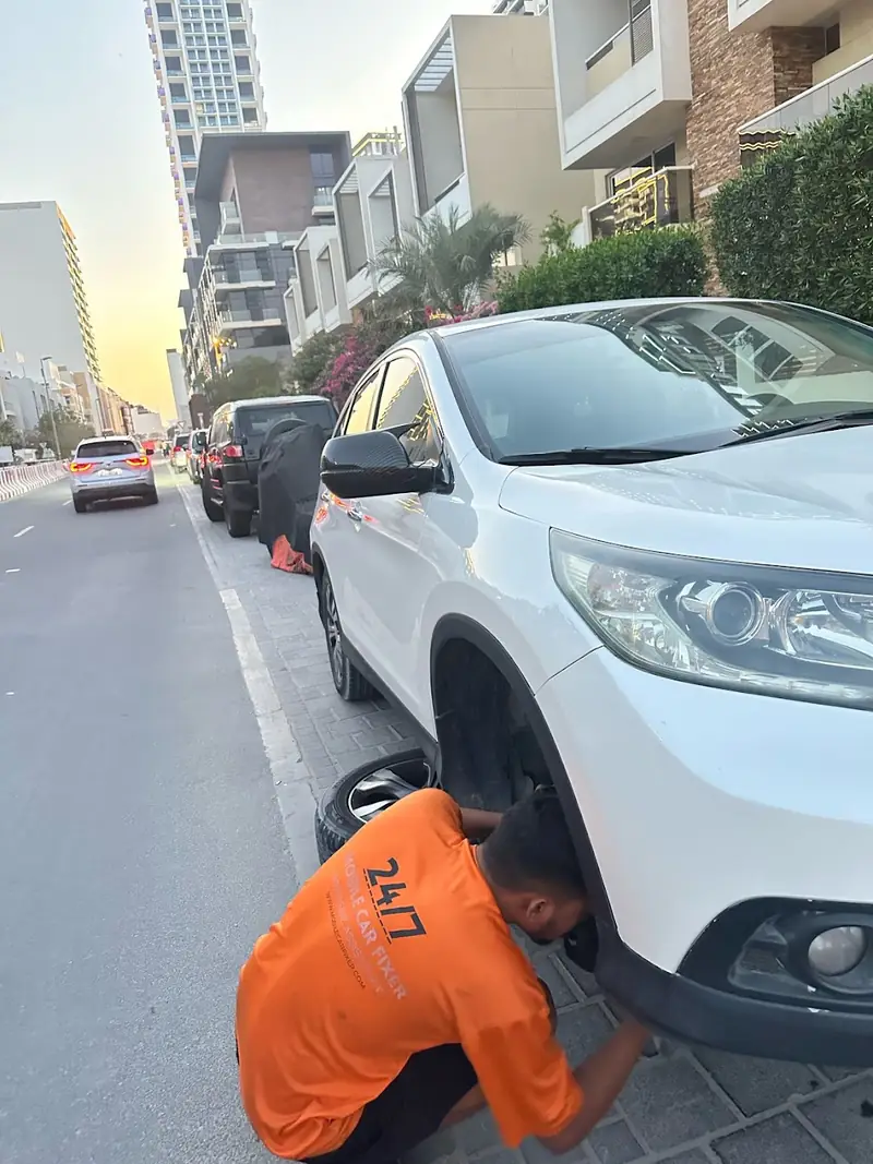 Technician kneeling at a car wheel by the roadside